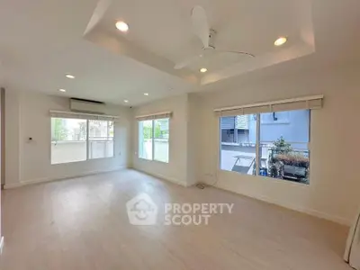 Spacious and bright living room with large windows and ceiling fan in modern home.