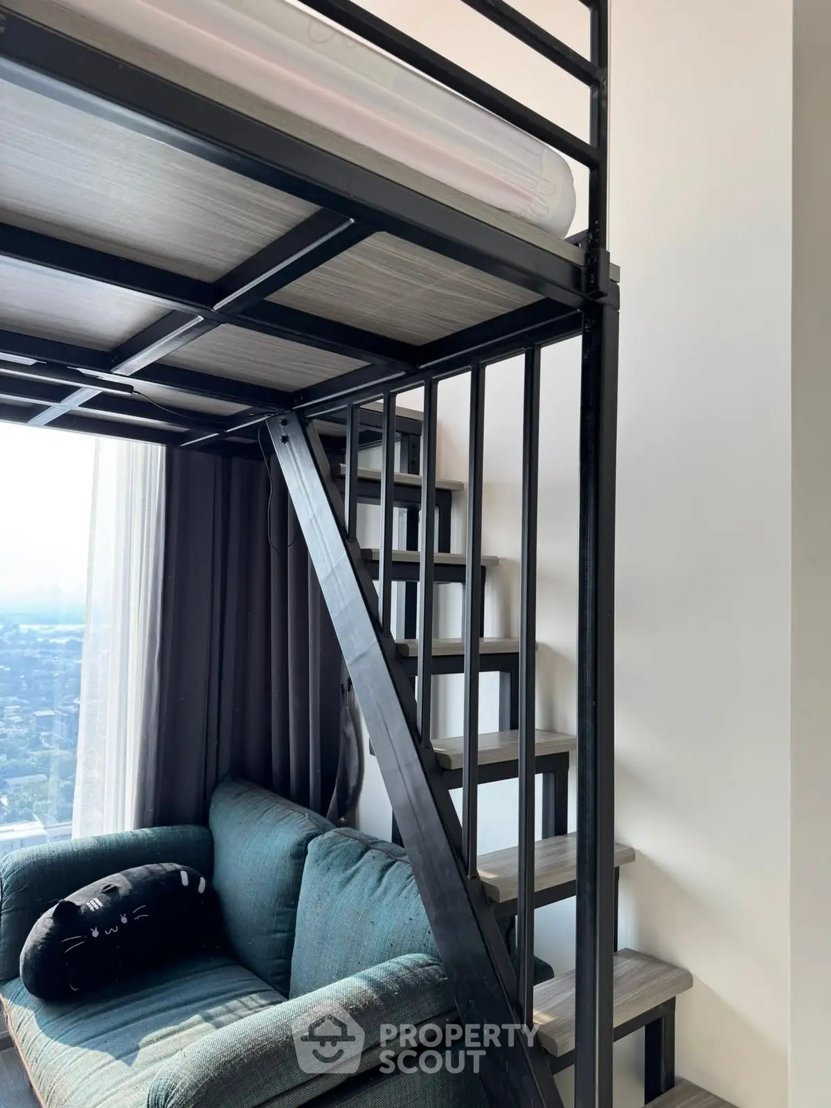 Modern loft apartment with stylish metal staircase and cozy seating area.