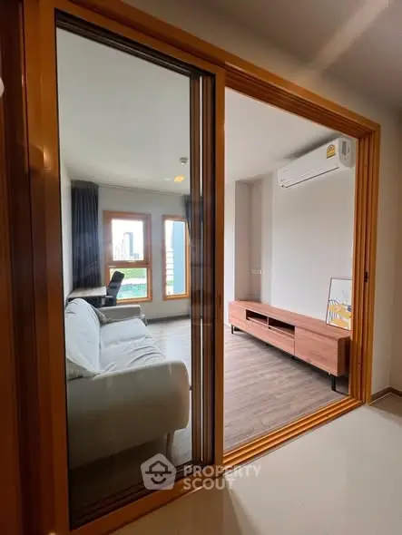 Modern living room with sleek furniture and large windows offering city views.