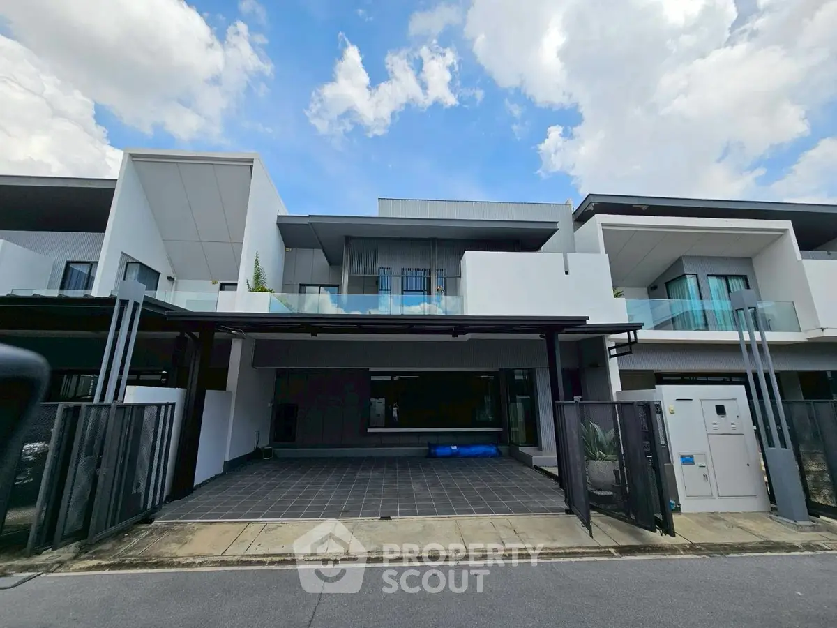Modern townhouse with sleek design and spacious driveway under a clear blue sky.