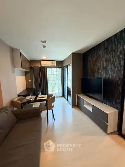 Modern living room with sleek furniture and large window offering natural light.