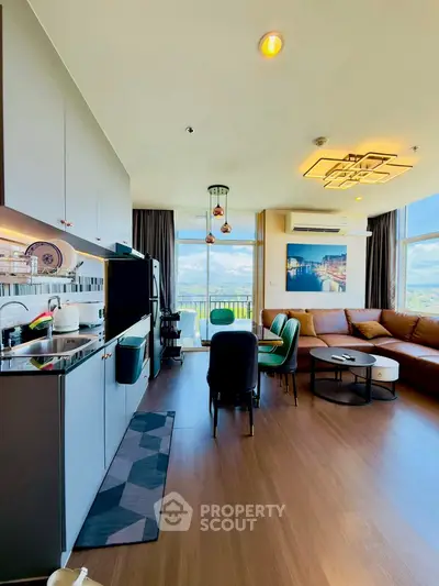 Modern open-layout living room with kitchen, featuring large windows and stylish decor.