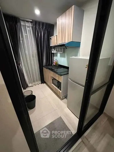 Modern compact kitchen with sleek appliances and stylish cabinetry in a cozy apartment setting.