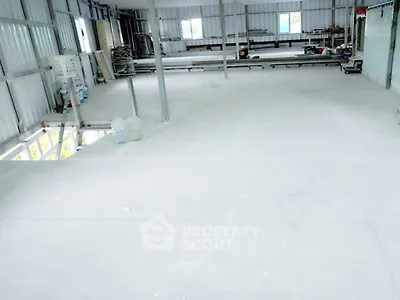 Spacious industrial-style interior with metal framework and large windows, ideal for creative workspace or storage.