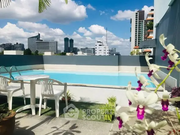 Stunning rooftop pool with city skyline views and lush greenery, perfect for relaxation and leisure.