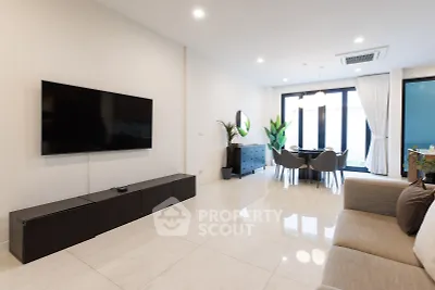 Spacious modern living room with sleek furniture and large TV, perfect for relaxation and entertainment.
