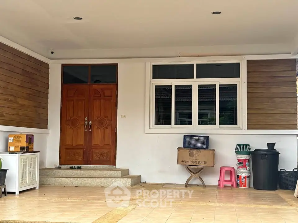 Charming house entrance with wooden door and tiled porch, perfect for welcoming guests.