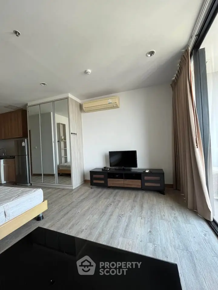 Modern living room with sleek design, featuring a TV stand, mirrored wardrobe, and large windows for natural light.