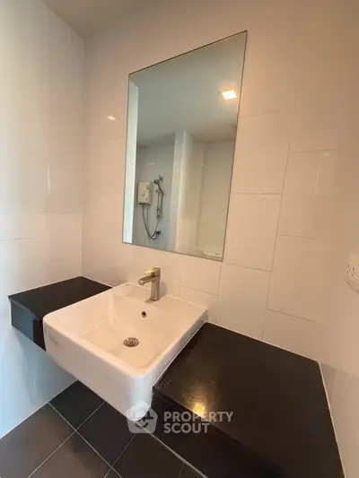 Modern bathroom with sleek sink and large mirror in contemporary apartment.