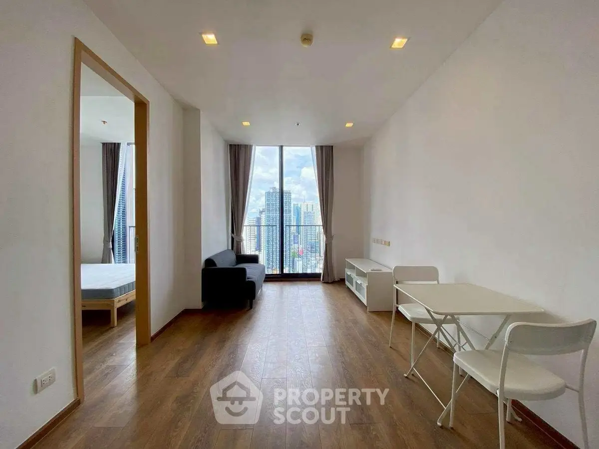 Modern apartment interior with city view, featuring wooden flooring and minimalist furniture.