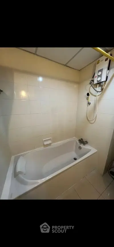 Compact bathroom with bathtub and wall-mounted water heater in modern apartment.