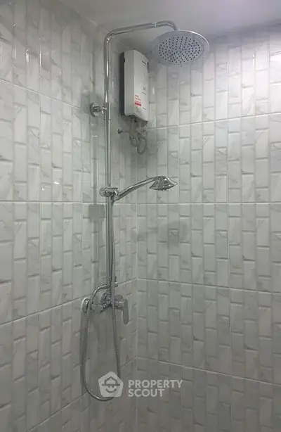 Modern bathroom with sleek shower and water heater, featuring elegant tile design.