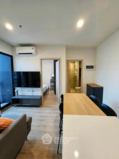 Modern apartment interior with open living and dining area, featuring sleek furniture and contemporary design.