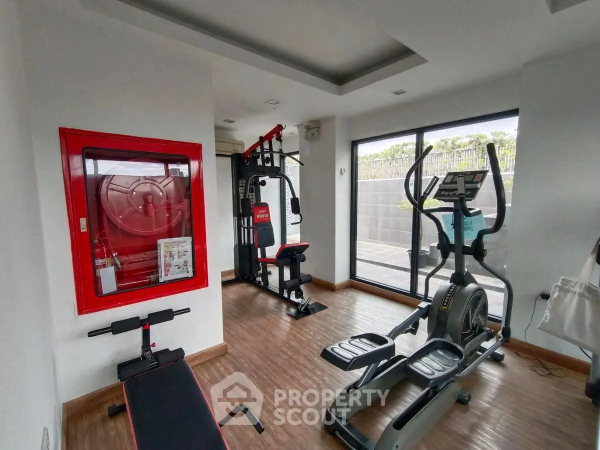 Modern gym with exercise equipment in a bright, spacious room with wooden flooring.