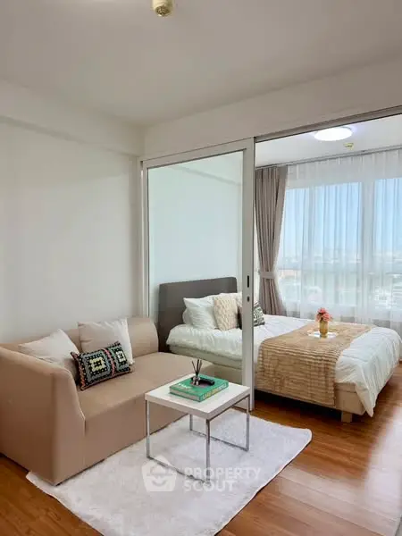 Modern studio apartment with cozy living area and bedroom, featuring large windows and stylish decor.