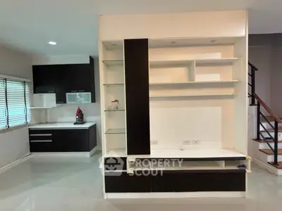 Modern kitchen with sleek cabinetry and open layout, featuring a stylish staircase and ample natural light.