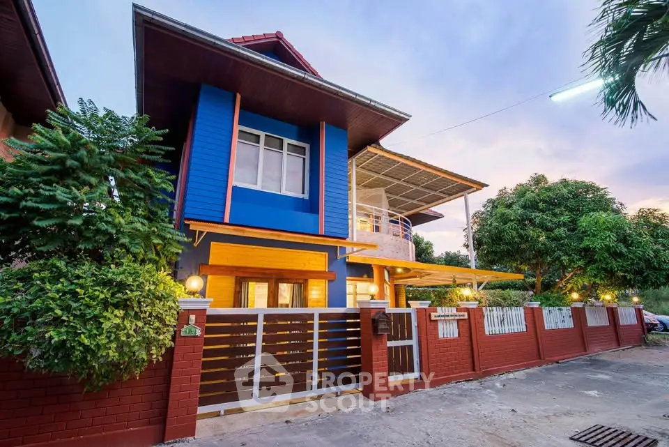 Charming two-story house with vibrant blue facade and spacious balcony in a serene neighborhood.
