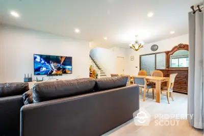 Spacious living room with modern furnishings, large flat-screen TV, and an inviting dining area, perfect for entertaining guests or family gatherings.