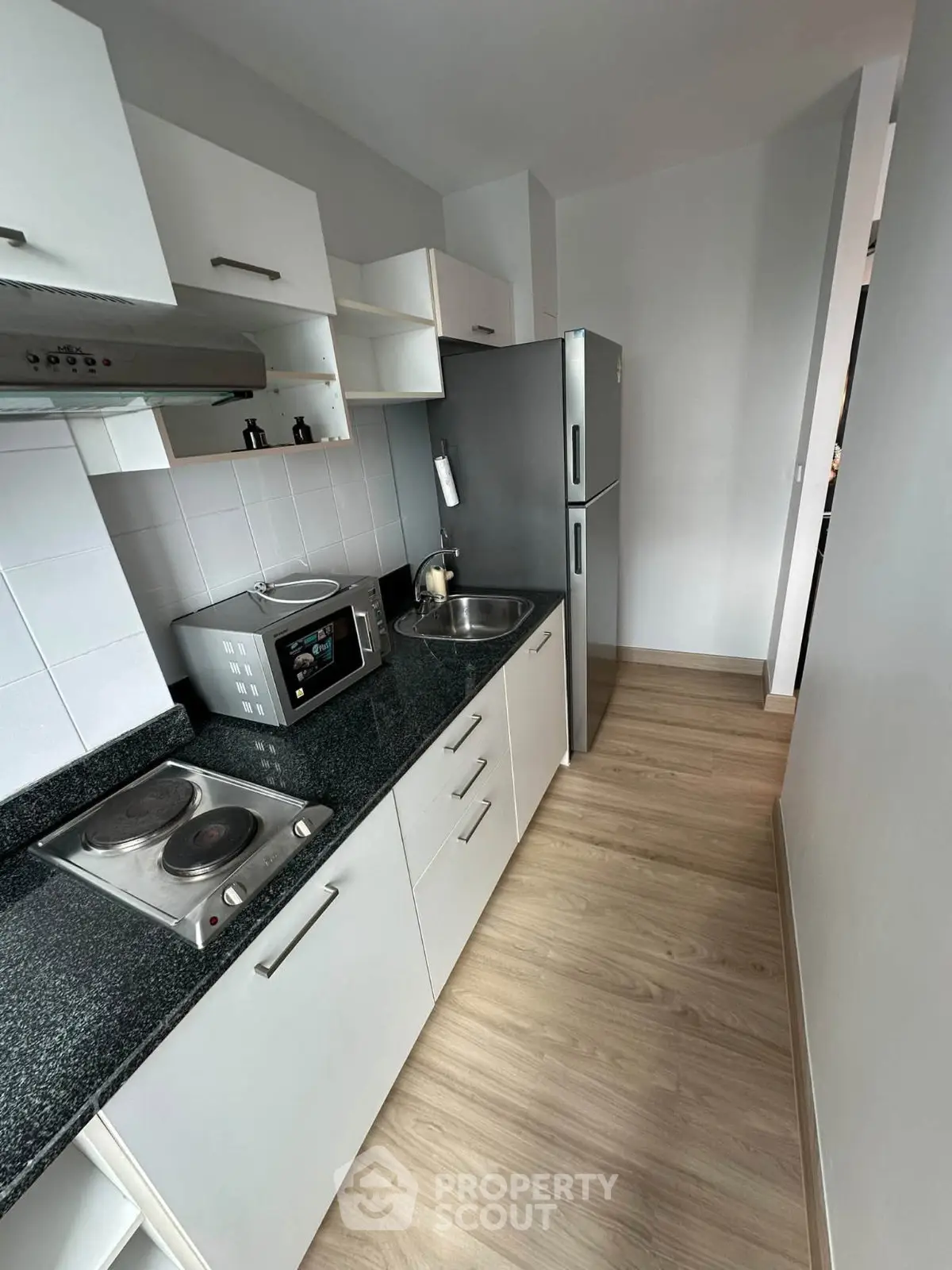 Modern compact kitchen with sleek appliances and wooden flooring