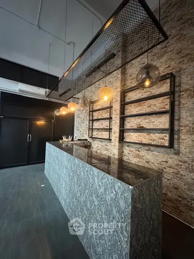 Modern industrial-style kitchen with marble countertop and exposed brick wall
