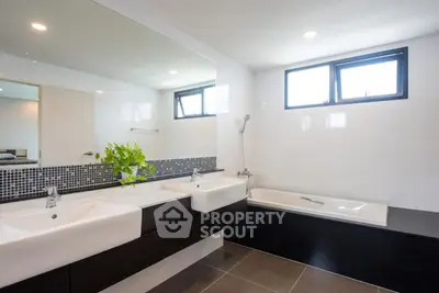 Modern bathroom with dual sinks and bathtub in stylish real estate property.