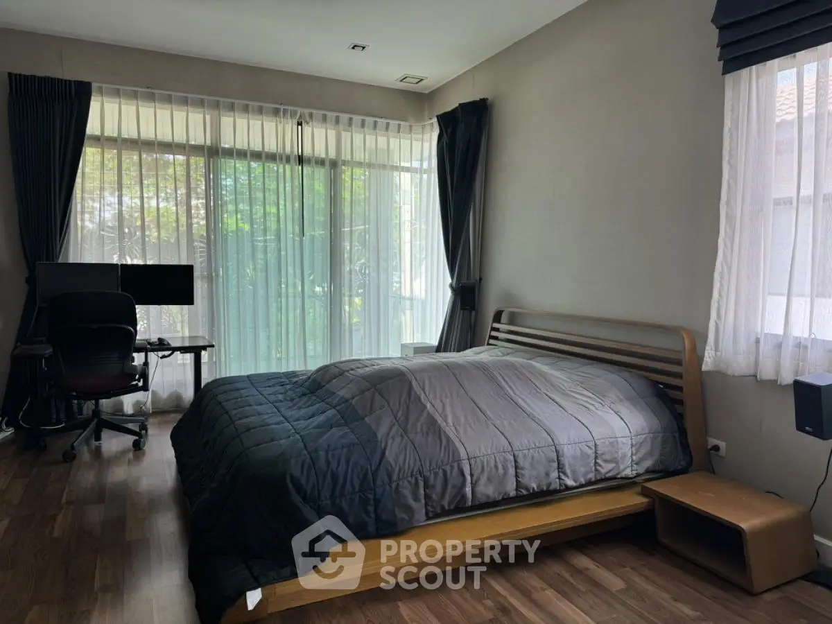 Spacious bedroom with modern decor and large windows offering natural light.