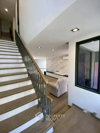 Modern interior with wooden staircase and spacious living area, perfect for contemporary living.