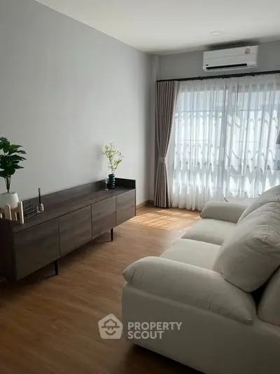Spacious living room with modern decor and large window for natural light.