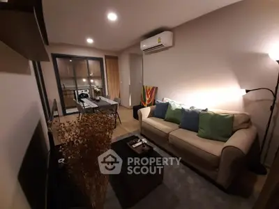 Cozy living room with modern decor and open layout to dining area, featuring a comfortable sofa and stylish lighting.