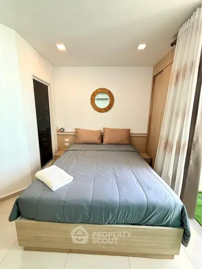 Cozy bedroom with modern decor and natural light, featuring a comfortable bed and stylish mirror.