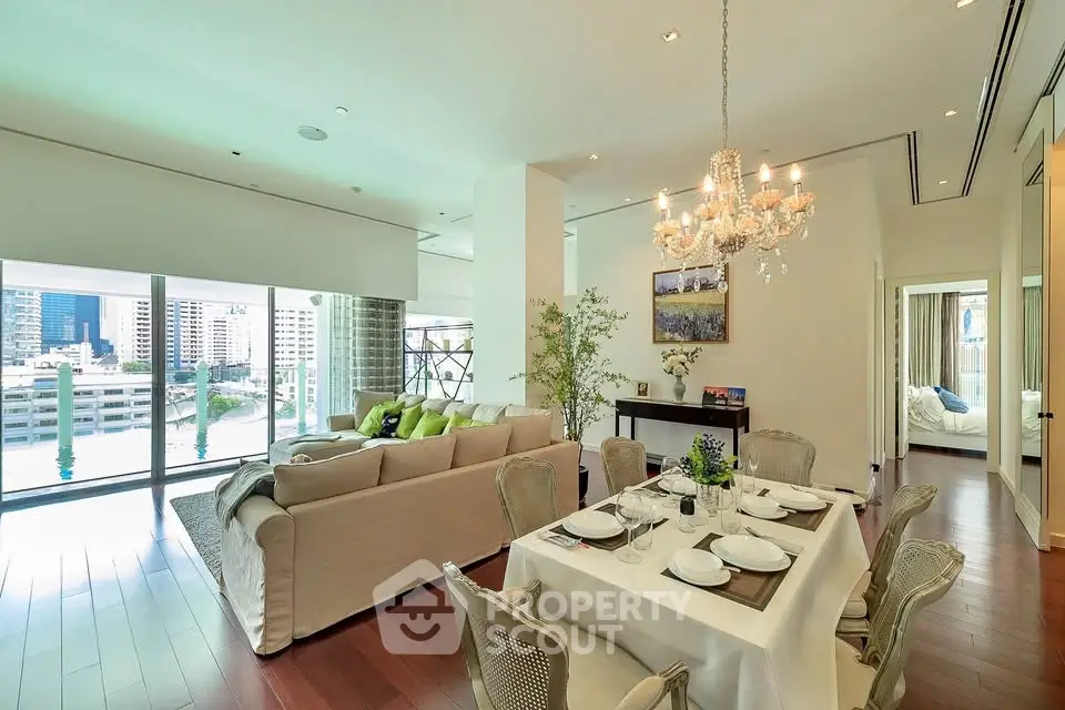 Luxurious open-plan living and dining area with elegant chandelier and city view.