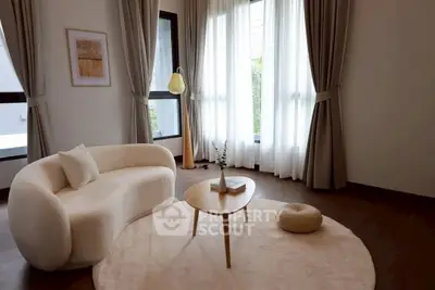 Elegant living room with modern sofa, round coffee table, and large windows with sheer curtains.