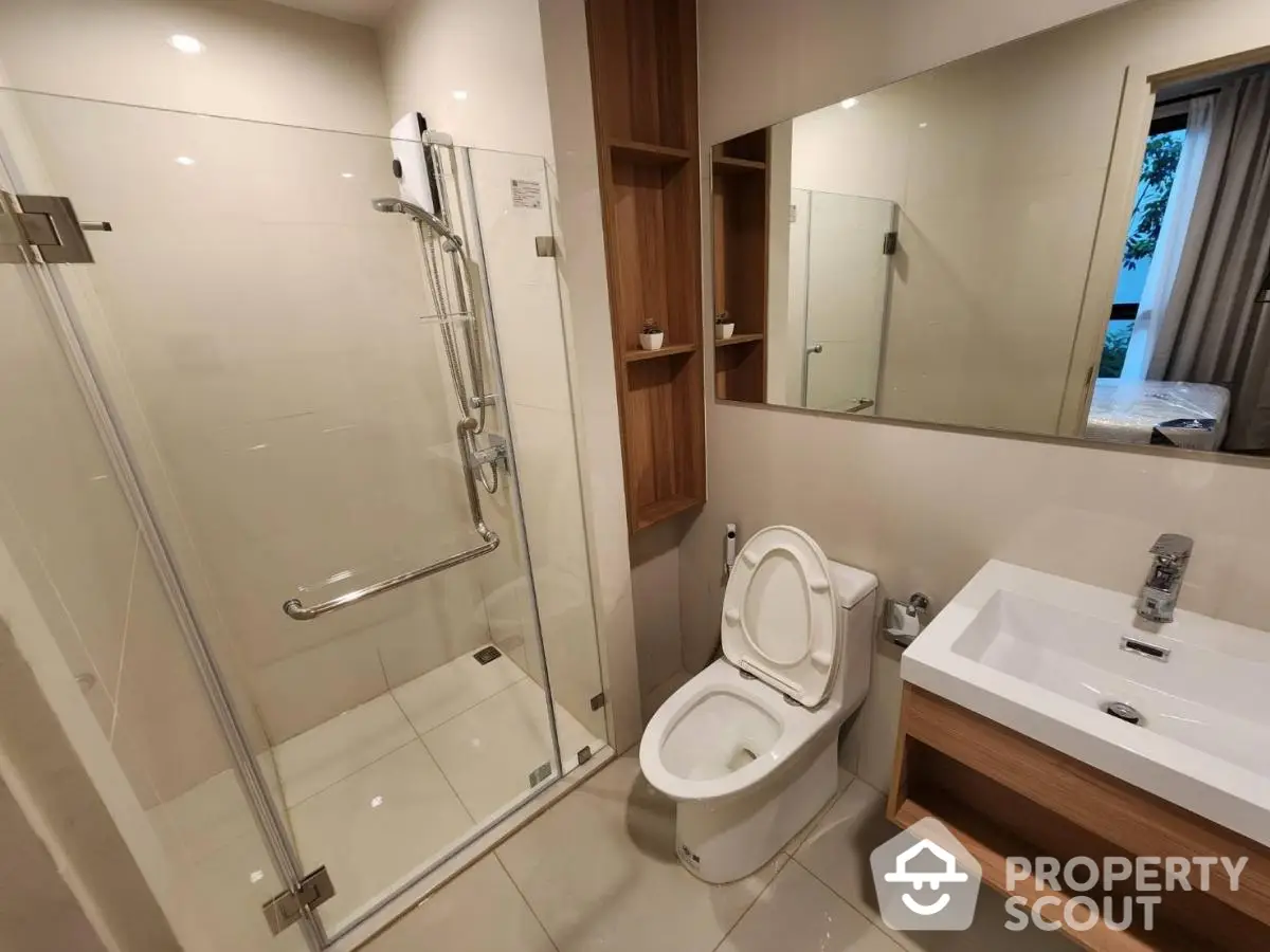 Modern bathroom with glass shower and sleek fixtures in contemporary apartment.