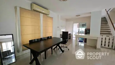 Spacious modern dining area with sleek black table, office chair, and staircase leading to upper floor.