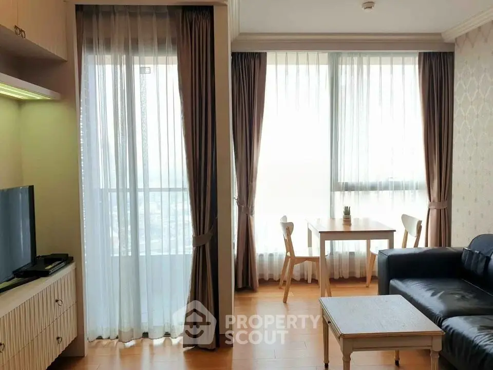 Bright living room with large windows, modern furniture, and wooden flooring.