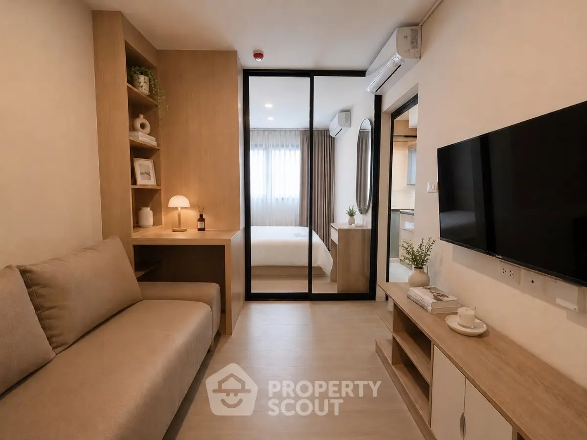 Modern living room with cozy sofa, TV, and view into a stylish bedroom through glass doors.