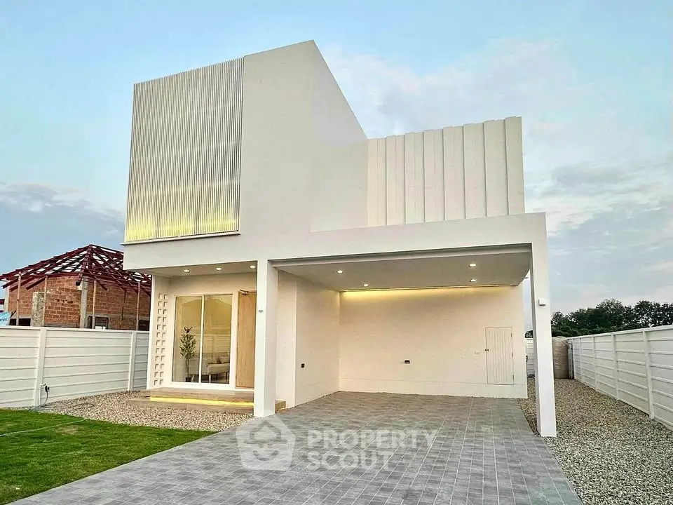 Modern minimalist white house with spacious driveway and sleek architectural design.