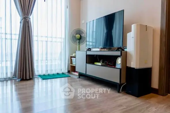 Modern living room with sleek TV setup and large window for natural light.