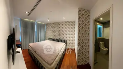 Spacious bedroom with stylish wallpaper and ensuite bathroom in modern apartment.