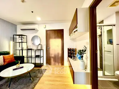 Modern living room with stylish decor and adjacent bathroom, featuring sleek furniture and warm lighting.