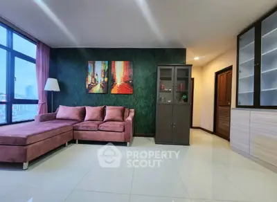 Spacious living room with modern decor and large windows offering city views.