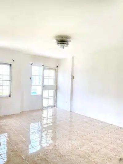 Bright and spacious living room with tiled flooring and large windows.