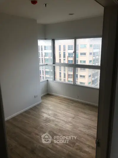 Bright empty room with large windows and city view, perfect for customization.