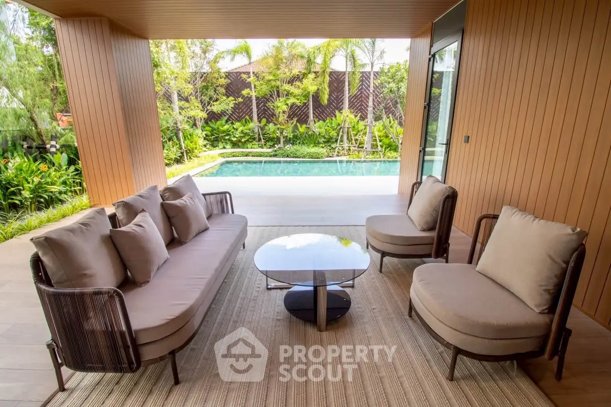 Luxurious outdoor seating area with pool view and lush greenery, perfect for relaxation and entertaining.