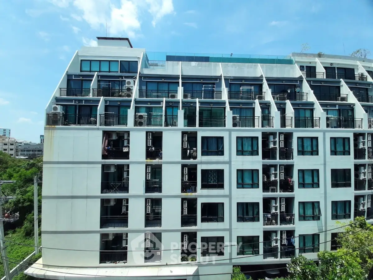 Modern apartment building with unique architectural design and lush greenery surroundings.