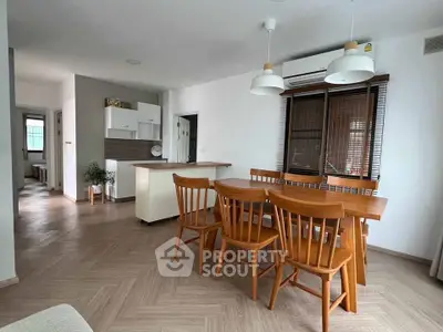 Spacious dining area with wooden furniture and modern lighting in a cozy apartment.