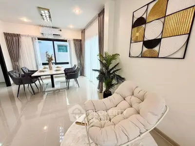 Elegant modern living room with stylish decor and dining area, featuring a plush chair and contemporary artwork.