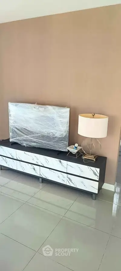 Modern living room with sleek TV stand and stylish lamp on glossy tiled floor.