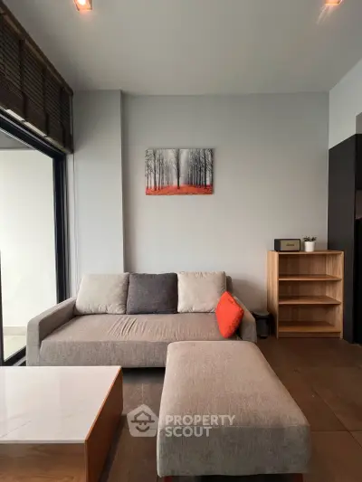 Modern living room with stylish sofa, ottoman, and wall art in a cozy apartment setting.