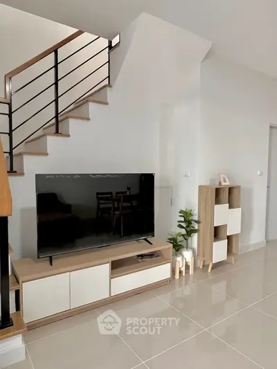 Modern living room with sleek TV stand and staircase, perfect for stylish urban living.